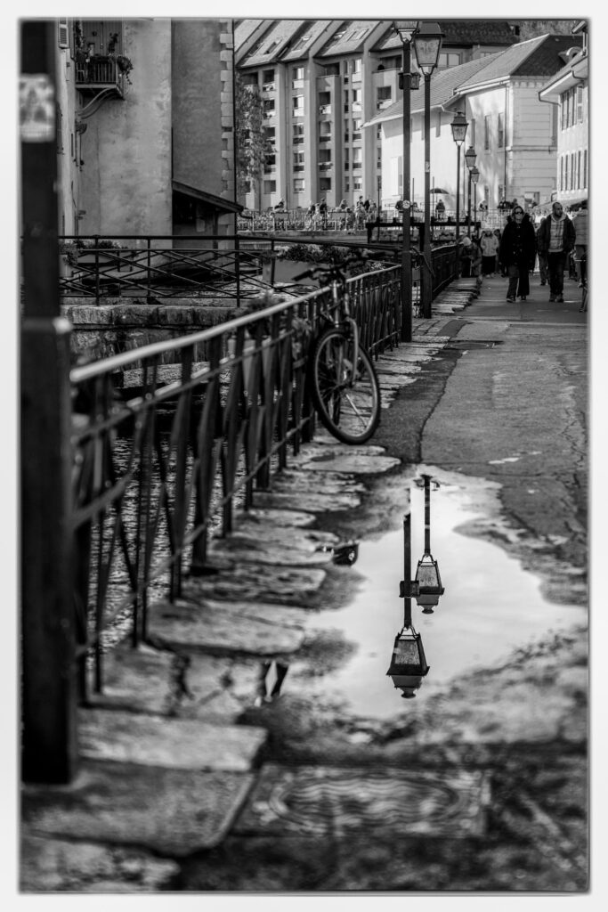 Photographie noir et blanc du reflet de lampadaires dans la vieille ville d'Annecy