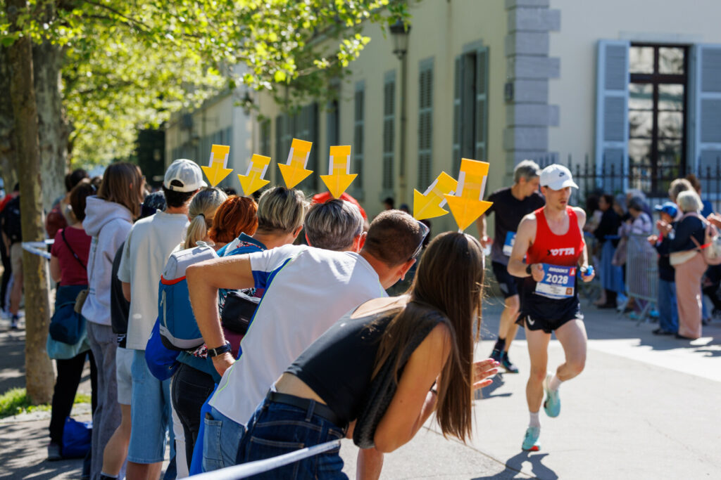 Groupe de supporters avec des flèches en carton sur la tête au marathon d’Annecy 2026