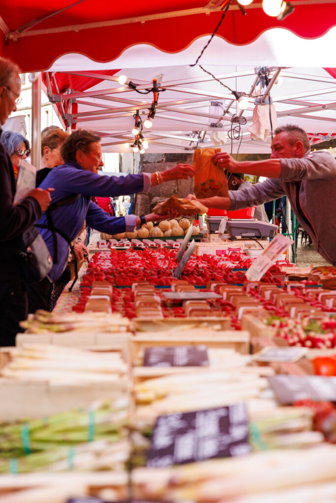 Cliente et marchand se passant des paquets de fruits au marché de la vieille ville à Annecy