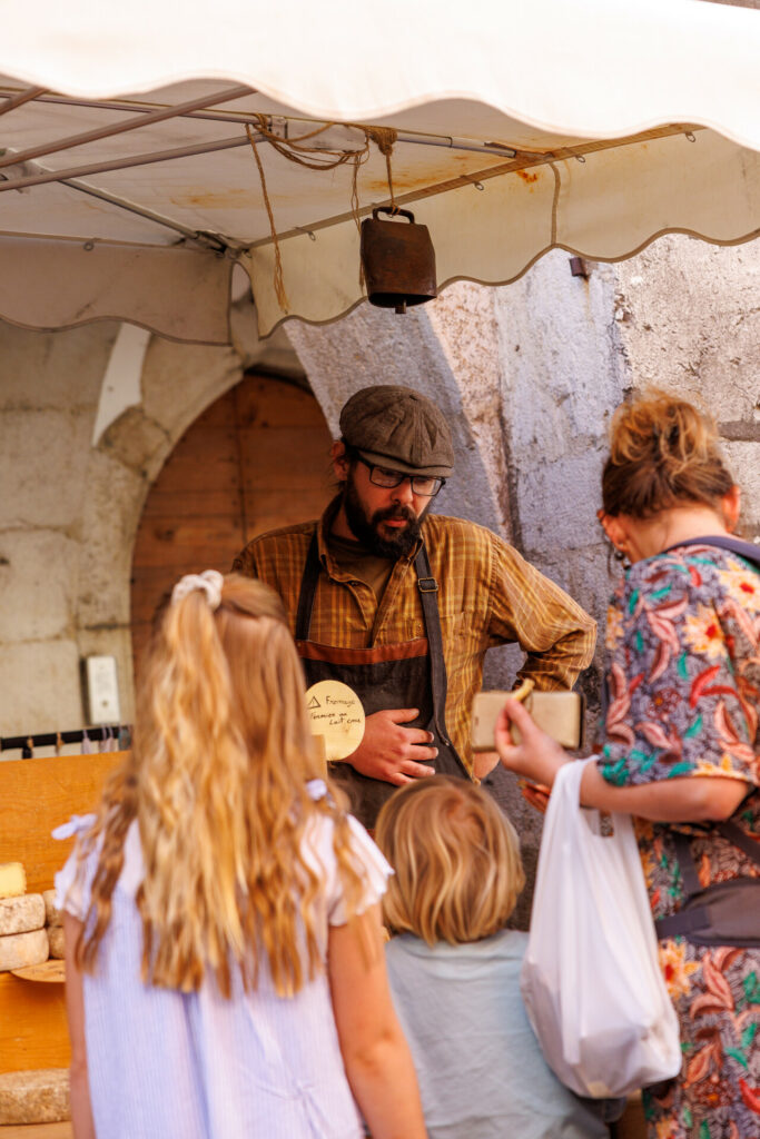 Fromager renseignant une cliente et ses enfants au marché de la vieille ville à Annecy